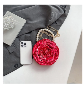 Detailed top view of red rose-shaped evening bag with pearl handle and golden chain