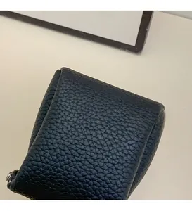Detail of black litchi grain leather mini pouch featuring a premium silver metal zipper