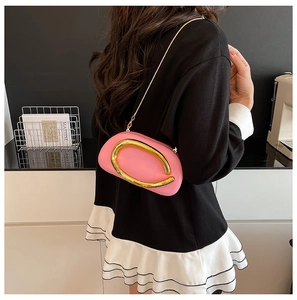 Pink acrylic clutch bag with gold ring and chain shown in a modern home setting