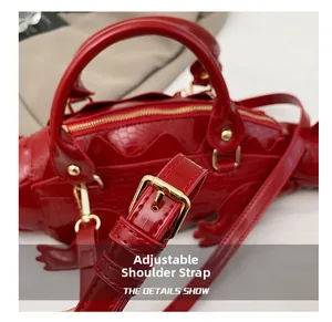 Detail shot of the adjustable shoulder strap on a red crocodile-shaped glossy handbag