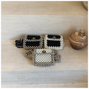 Detailed view of mini woven pearl bags with camellia accents and metallic chain straps