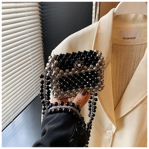 Detail of a mini woven bead bag featuring a black camellia flower with a pearl center