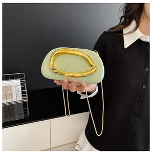 Detail of light green clutch bag with bold gold handle and elegant chain strap