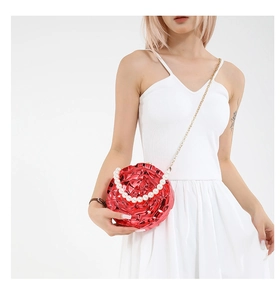 Detail of red rose evening bag with pearl handle and golden chain on white dress