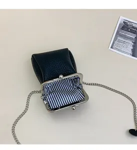 Detail of mini black lychee leather lipstick bag with metal clasp and striped lining