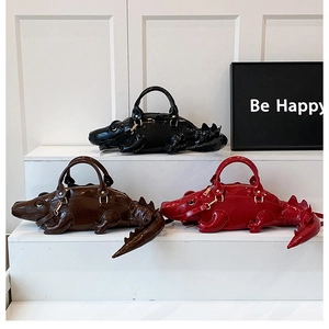 Three creative crocodile shaped bags in black, red, and brown on white pedestals