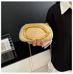 Detail of champagne gold clutch with gold C-shaped metal buckle and slim shoulder strap