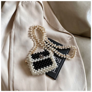 Detail of woven mini bag with pearl beads and a golden camellia flower metal clasp