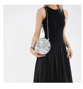 Close-up of silver floral晚宴包 handbag with metallic petals and chain strap on a black dress