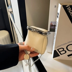 Detail of cream lychee texture leather mini purse with silver chain and clasp closure