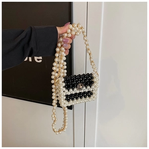 Detail of a mini woven pearl bag with camellia buckle and golden chain strap
