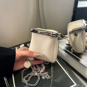 Close-up of white mini kiss-lock pouch with lychee texture and silver chain strap