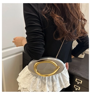 Detail view of silver oval evening bag with large gold C-clasp and metal chain strap