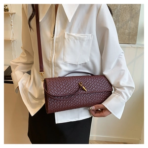 Détail du sac en cuir tressé bordeaux avec un fermoir nœud en métal doré et bandoulière