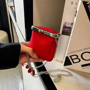 Detail of red lychee grain leather mini bag featuring silver metal clasp and chain strap
