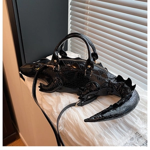 Detail of creative black crocodile shaped handbag with glossy embossed faux leather texture