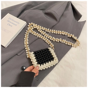 Detail of a mini woven pearl bag with black and white beads and elegant gold chain strap