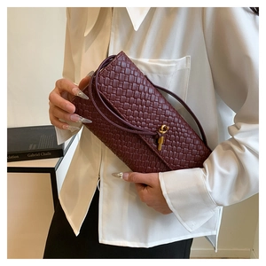 Détail du sac baguette tressé bordeaux avec un fermoir magnétique à nœud doré