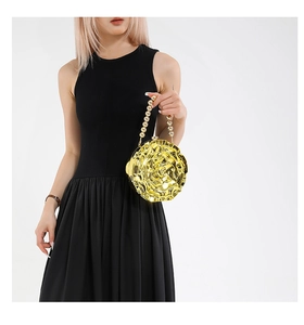 Detailed shot of golden rose evening bag with 3D petals and beaded handle on model