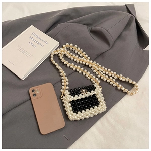 Detailed macro view of mini pearl woven crossbody bag with gold camellia buckle accessory