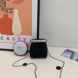 Close-up of black litchi leather mini coin purse with silver clasp and chain strap