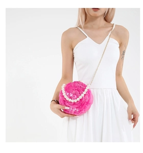 Detail of pink acrylic rose handbag with pearl handle and golden chain on model