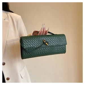 Détail d'une pochette en cuir tressé vert foncé avec un fermoir en métal doré en forme de nœud