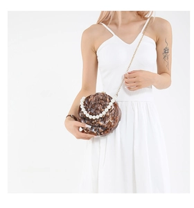Detail of round marble texture evening bag with pearl handle and gold chain strap
