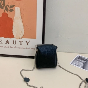 Detail of mini black pebbled leather crossbody bag with silver clasp and chain