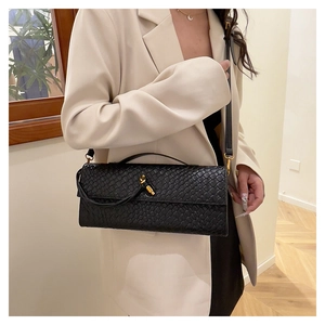 Détail du sac baguette tressé noir avec fermoir tournant doré et bandoulière réglable