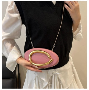 Detail of pink oval evening bag with decorative gold metal ring handle and chain strap