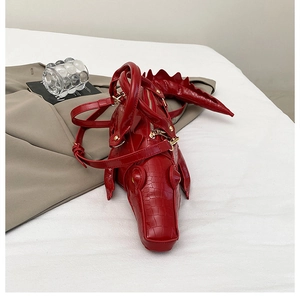 Detailed view of red crocodile-shaped bag with realistic 3D textures and top zipper
