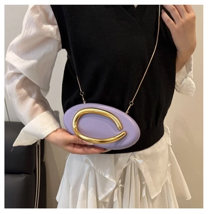 Model view of purple round clutch bag with large gold metal handle and chain strap
