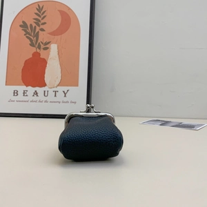 Close-up of a mini navy blue pebble leather coin purse with a silver metal clasp