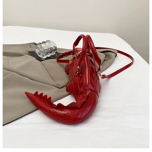 Detailed macro view of the glossy red crocodile-shaped bag with embossed texture and gold zipper