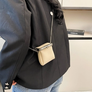 Close-up of beige lychee leather mini bag with metal clasp and chain on model