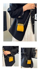 Close-up of bright yellow mini leather lipstick bag with silver chain and metal clasp