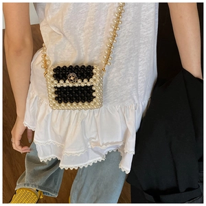 Detailed shot of a woven pearl mini crossbody bag with a gold camellia clasp on a model