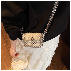 Close-up of woven pearl crossbody bag featuring a black camellia charm and chain strap