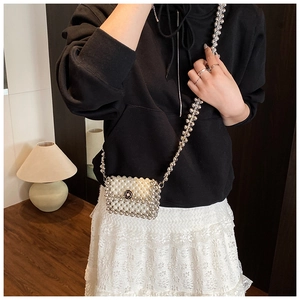 Detail of mini woven pearl bag with black camellia clasp and silver ball chain strap