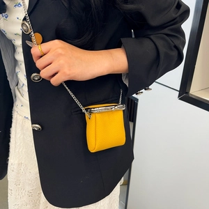 Close-up of a yellow pebble leather mini bag with silver kiss-lock and chain strap