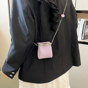 Mini lavender pebbled leather lipstick bag with silver chain worn by a model in a suit