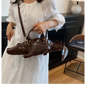 Detail of creative dark brown crocodile-shaped crossbody bag with realistic animal texture