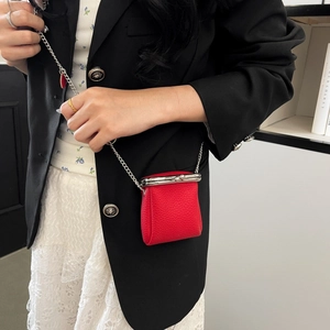 Detail of red litchi leather mini clip bag with silver chain and heart pendant