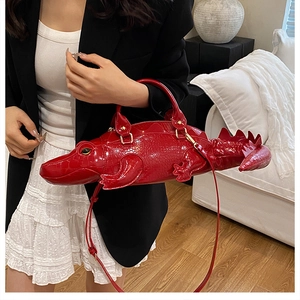 Detail of red crocodile-shaped bag showing embossed leather texture and creative fin spikes