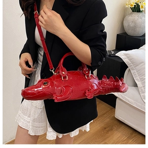 Creative red crocodile shape handbag worn by a model in a stylish black and white outfit