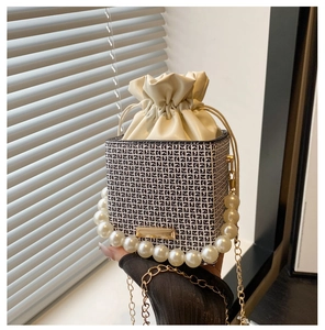 Detailansicht des Perlenfgrinns und der geometrischen Kordelzug-Beuteltasche mit Goldkette