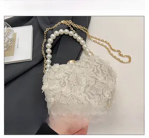 Detail of heart-shaped lace evening bag with pearl handle and golden chain strap
