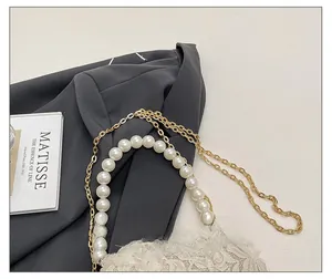 Detailed close-up of lace floral texture with faux pearl handle and gold metal chain strap