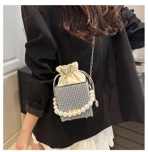 Detail of monogram box bucket bag with pearl handle and satin drawstring lining
